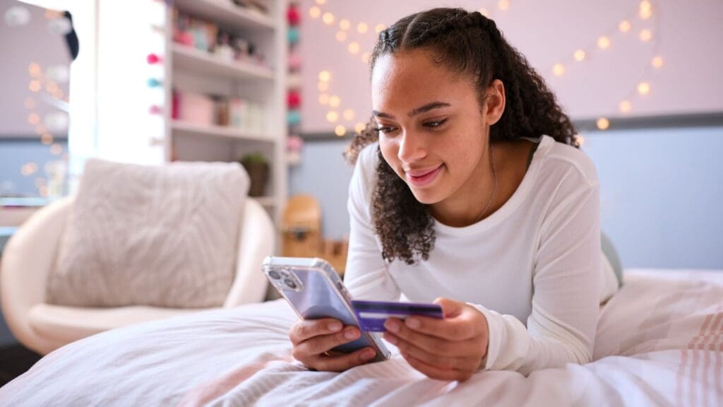 teenage girl sitting on her bed looking at her mobile phone